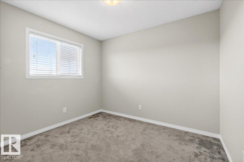 This room features light grey walls, grey carpet, and a window with white blinds - 17023 38 Street Nw, Edmonton, AB 