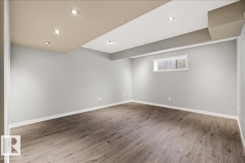 Versatile room featuring light grey walls, light wood-look flooring, recessed lighting, and a window with blinds - 17023 38 Street Nw, Edmonton, AB 