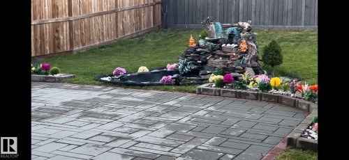 The property features a paved patio area, a landscaped garden with a decorative waterfall, and a well-maintained lawn - 17023 38 Street Nw, Edmonton, AB - Outdoor