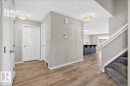 Entryway featuring light wood-look flooring, neutral wall paint, and a carpeted staircase - 17023 38 Street Nw, Edmonton, AB 