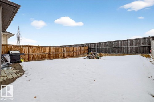 The property features a spacious backyard with a paved patio area, surrounded by a wooden fence - 17023 38 Street Nw, Edmonton, AB - Outdoor