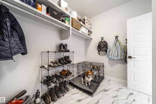 This functional space features white walls, overhead shelving, and a patterned tile floor - 3514 49 Avenue, Beaumont, AB - Indoor With Storage