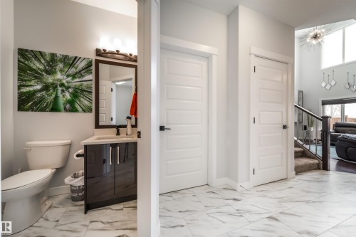 This property features a bathroom with a toilet, a vanity with a dark cabinet, and a mirror - 3514 49 Avenue, Beaumont, AB - Indoor Photo Showing Bathroom