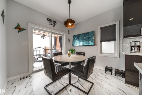 This dining area features a modern pendant light fixture and marble-look tiled flooring - 3514 49 Avenue, Beaumont, AB - Indoor Photo Showing Dining Room
