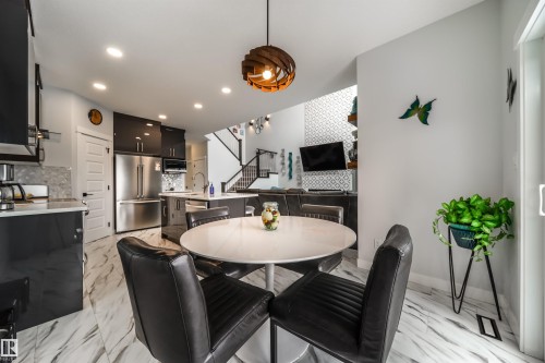 The property features a dining area with a round white table, surrounded by four dark chairs - 3514 49 Avenue, Beaumont, AB - Indoor Photo Showing Dining Room