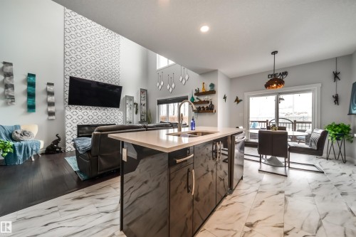 The open concept living area features high ceilings, dark hardwood flooring, and a modern kitchen island with a light-colored countertop - 3514 49 Avenue, Beaumont, AB - Indoor Photo Showing Kitchen With Double Sink