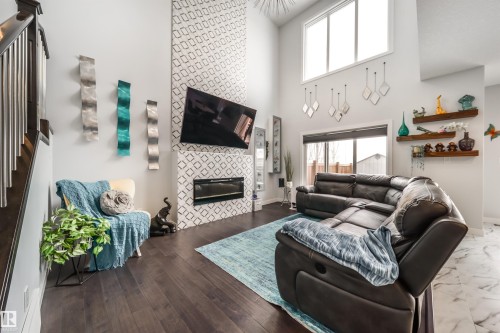The living room features high ceilings, dark wood flooring, and a fireplace with a decorative tile surround - 3514 49 Avenue, Beaumont, AB - Indoor Photo Showing Living Room With Fireplace