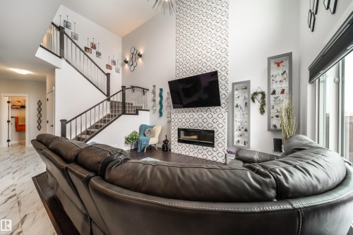 Spacious living area featuring high ceilings, a fireplace, and a staircase with dark wood railings - 3514 49 Avenue, Beaumont, AB - Indoor Photo Showing Living Room With Fireplace