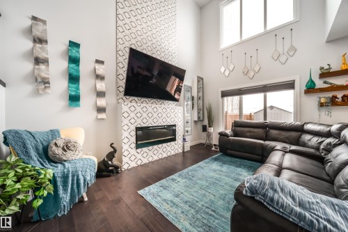The living room features high ceilings, dark wood flooring, and a fireplace with a decorative tiled surround - 3514 49 Avenue, Beaumont, AB - Indoor Photo Showing Living Room With Fireplace