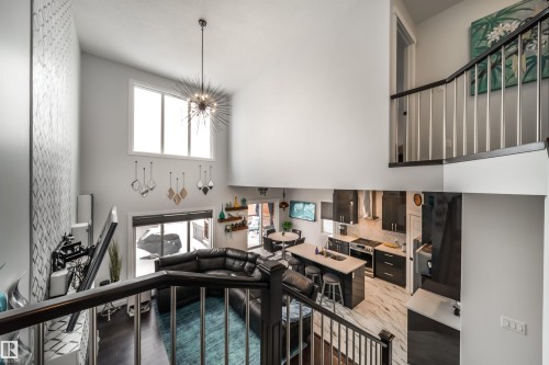 This property features an open-concept living space with high ceilings, a modern kitchen with a center island, and a living area with dark flooring - 3514 49 Avenue, Beaumont, AB - Indoor Photo Showing Other Room