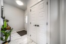 The entry features light-colored walls, white paneled doors with dark hardware, and a white and grey patterned tile floor - 3514 49 Avenue, Beaumont, AB  - Indoor Photo Showing Other Room 