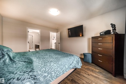 Room featuring wood-look flooring, a flush mount ceiling light, and a wall-mounted television - 3514 49 Avenue, Beaumont, AB - Indoor Photo Showing Bedroom