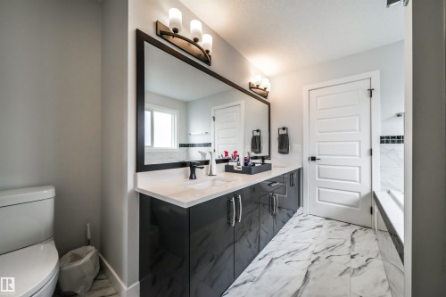 Bathroom featuring a double vanity with dark cabinetry, light countertops, and a large mirror - 3514 49 Avenue, Beaumont, AB - Indoor Photo Showing Bathroom