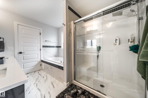 The bathroom features a glass-enclosed shower with a built-in seat and a wall-mounted showerhead - 3514 49 Avenue, Beaumont, AB - Indoor Photo Showing Bathroom