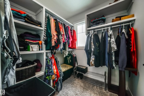Walk-in closet featuring built-in shelving, hanging rods, and a window providing natural light - 3514 49 Avenue, Beaumont, AB - Indoor With Storage