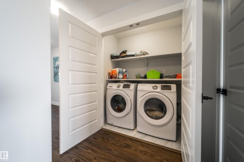 Dedicated laundry area featuring a washer and dryer, an overhead shelf, and white paneled doors - 3514 49 Avenue, Beaumont, AB - Indoor Photo Showing Laundry Room