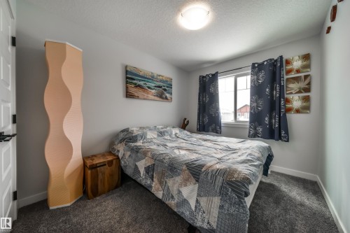 This room features a window with dark patterned curtains, light grey walls, and a grey carpet - 3514 49 Avenue, Beaumont, AB - Indoor Photo Showing Bedroom