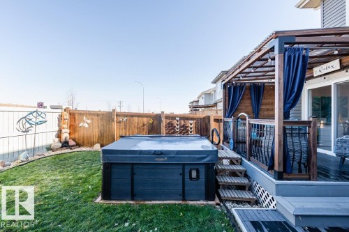 The property features an extensive backyard with a well-maintained lawn, a covered hot tub, and a wooden fence - 3514 49 Avenue, Beaumont, AB - Outdoor