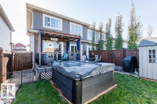 The property features a private backyard with a covered hot tub, a wooden deck with a pergola, and a shed, all enclosed by a wooden fence - 3514 49 Avenue, Beaumont, AB - Outdoor With Exterior