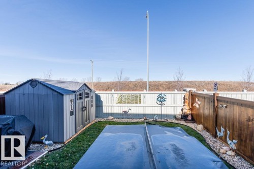 The property features a fenced yard with a storage shed, a covered pool, and a decorative rock border - 3514 49 Avenue, Beaumont, AB - Outdoor
