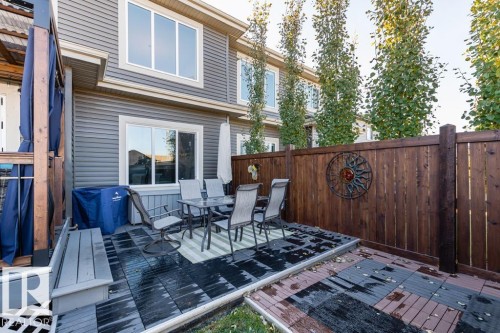 The property features a spacious deck area with a dining set and an umbrella, complemented by a privacy fence and mature trees - 3514 49 Avenue, Beaumont, AB - Outdoor With Deck Patio Veranda