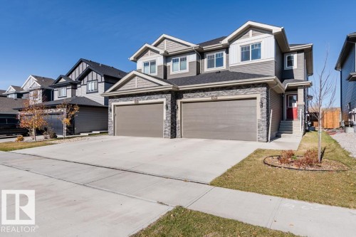 The property features a two-story design with a stone and siding exterior, two attached garages, and a concrete driveway - 3514 49 Avenue, Beaumont, AB - Outdoor With Facade