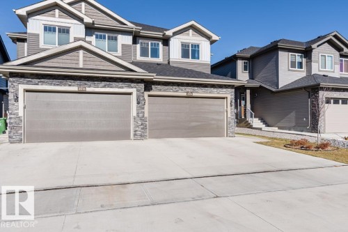 The property features a two-car garage with a concrete driveway, stone accents on the facade, and a pitched roof - 3514 49 Avenue, Beaumont, AB - Outdoor With Facade