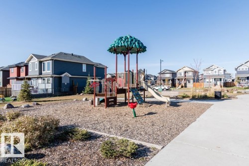 Neighborhood park featuring a playground with a slide and a concrete pathway - 3514 49 Avenue, Beaumont, AB - Outdoor