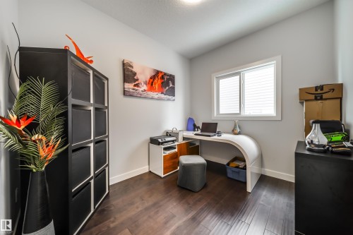 This room features rich, dark wood flooring and a window with horizontal blinds, providing natural light - 3514 49 Avenue, Beaumont, AB - Indoor Photo Showing Office
