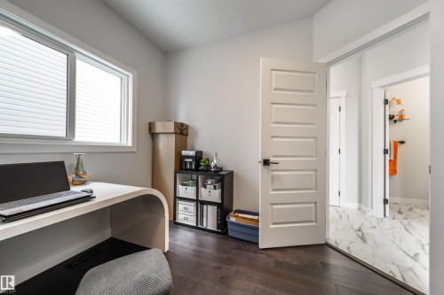 This room features dark hardwood flooring and a window with blinds, allowing for adjustable natural light - 3514 49 Avenue, Beaumont, AB - Indoor Photo Showing Office