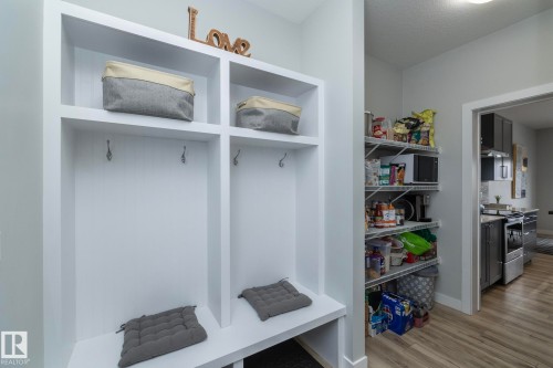 Entryway featuring built-in storage with hooks and seating, alongside a pantry with wire shelving, and wood-style flooring - 20650 94A Avenue, Edmonton, AB - Indoor Photo Showing Other Room