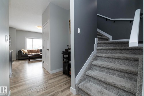 Entryway featuring light wood-look flooring, a white door, and a carpeted staircase with a white handrail - 20650 94A Avenue, Edmonton, AB - Indoor Photo Showing Other Room