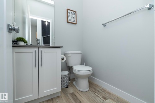 The bathroom features a modern vanity with a gray countertop, a mirror, and a white toilet - 20650 94A Avenue, Edmonton, AB - Indoor Photo Showing Bathroom