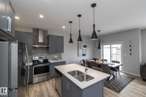 Modern kitchen and dining area with stainless steel appliances, grey cabinetry, a light-colored countertop, and light wood-style flooring - 20650 94A Avenue, Edmonton, AB - Indoor Photo Showing Kitchen With Double Sink With Upgraded Kitchen