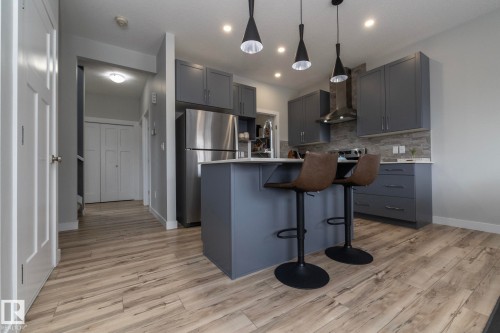The kitchen features a functional island with seating, stainless steel appliances, grey cabinetry, and a light-toned backsplash - 20650 94A Avenue, Edmonton, AB - Indoor Photo Showing Kitchen With Upgraded Kitchen