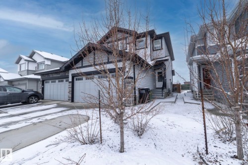 The property features light-colored siding, dark trim, and a prominent front-facing garage with two garage doors - 20650 94A Avenue, Edmonton, AB - Outdoor With Facade