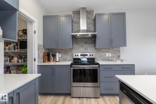 Kitchen featuring light grey cabinetry, stainless steel appliances, light-colored countertops, and a stone-style backsplash - 20650 94A Avenue, Edmonton, AB - Indoor Photo Showing Kitchen