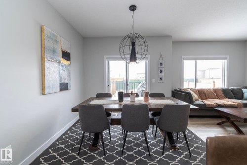 The dining area features a modern spherical chandelier, light-toned walls, and a large window providing natural light - 20650 94A Avenue, Edmonton, AB - Indoor Photo Showing Dining Room