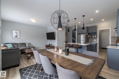 Open concept living area featuring a dining table with seating, a living room with a sectional sofa, and a kitchen with an island and stainless steel refrigerator - 20650 94A Avenue, Edmonton, AB - Indoor Photo Showing Other Room