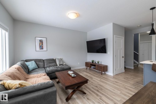 This inviting living area features light-colored flooring, light grey walls, and a large window providing natural light - 20650 94A Avenue, Edmonton, AB - Indoor Photo Showing Living Room