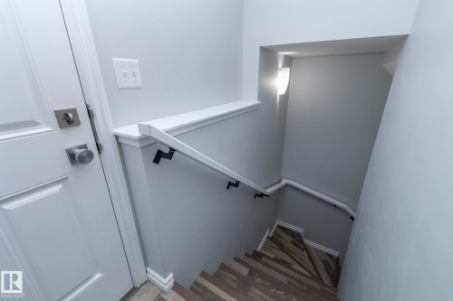 Stairwell with a white handrail, light gray walls, and multi-tone wood-look flooring - 20650 94A Avenue, Edmonton, AB - Indoor