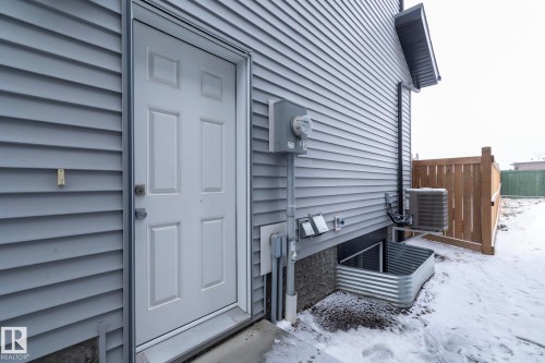 The property features light gray horizontal siding, a white exterior door, and a wooden fence - 20650 94A Avenue, Edmonton, AB - Outdoor With Exterior