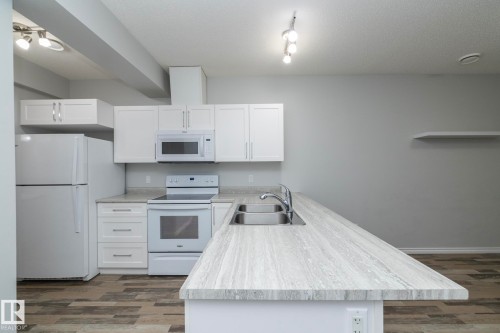 The kitchen features white cabinetry and appliances, a double basin sink, and ample countertop space - 20650 94A Avenue, Edmonton, AB - Indoor Photo Showing Kitchen With Double Sink