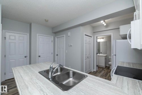 Kitchen area featuring a double basin stainless steel sink with a chrome faucet, light-colored countertops, and white appliances - 20650 94A Avenue, Edmonton, AB - Indoor Photo Showing Other Room