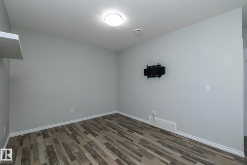 This room features light grey walls and multi-toned wood plank flooring, complemented by white baseboards - 20650 94A Avenue, Edmonton, AB - Indoor Photo Showing Other Room