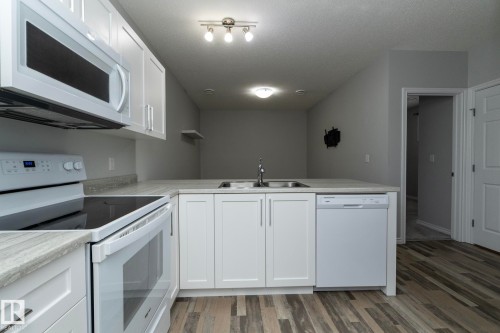 The kitchen features white cabinetry, light countertops, and wood-look flooring - 20650 94A Avenue, Edmonton, AB - Indoor Photo Showing Kitchen With Double Sink
