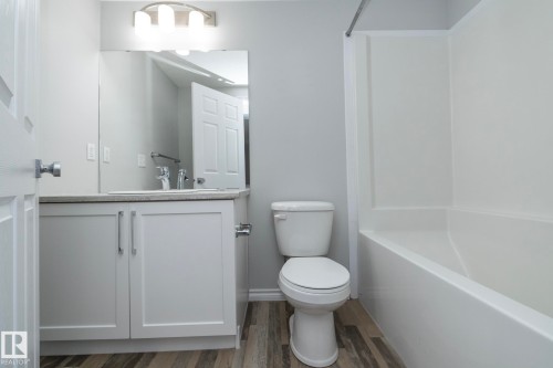 The bathroom features a vanity with white cabinetry and a light-colored countertop, a white toilet, and a white bathtub with a shower kit - 20650 94A Avenue, Edmonton, AB - Indoor Photo Showing Bathroom