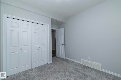 This room features soft gray carpeting, light gray walls, and white bi-fold closet doors - 20650 94A Avenue, Edmonton, AB - Indoor