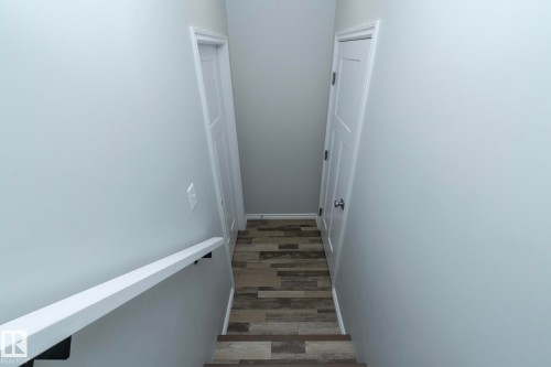 Staircase with light gray walls, a white handrail, and wood-look flooring - 20650 94A Avenue, Edmonton, AB - Indoor Photo Showing Other Room