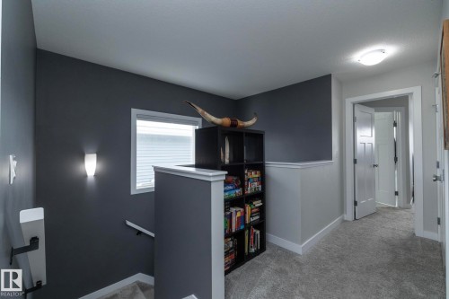 Landing area featuring dark and light gray painted walls, a window with blinds, and light gray carpeting - 20650 94A Avenue, Edmonton, AB - Indoor